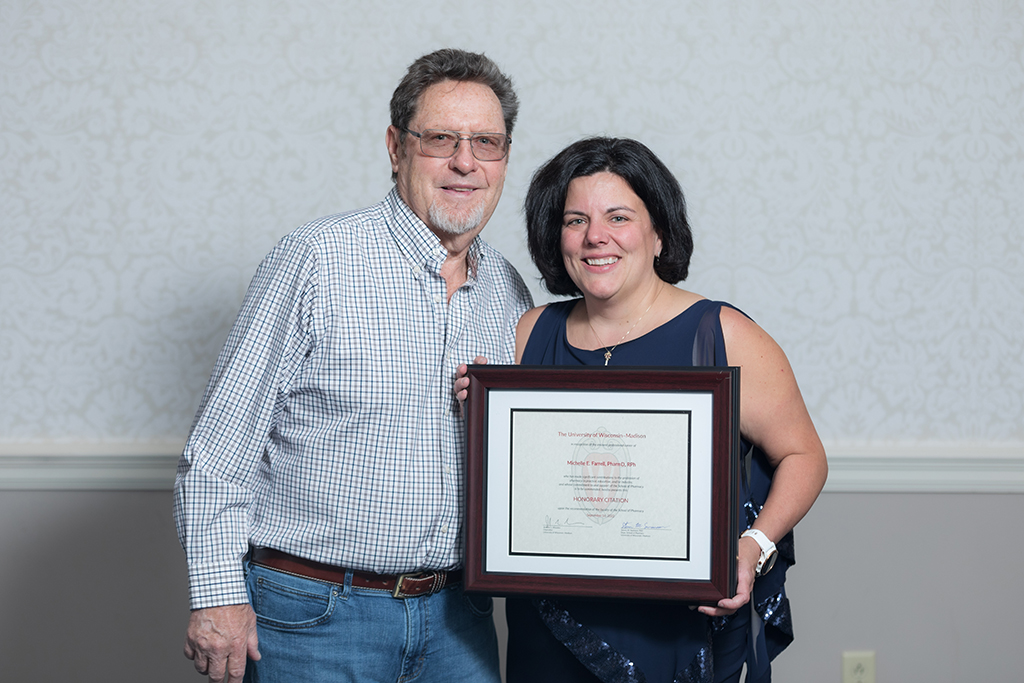 Michelle Farrell with her husband, holding her citation of merit award