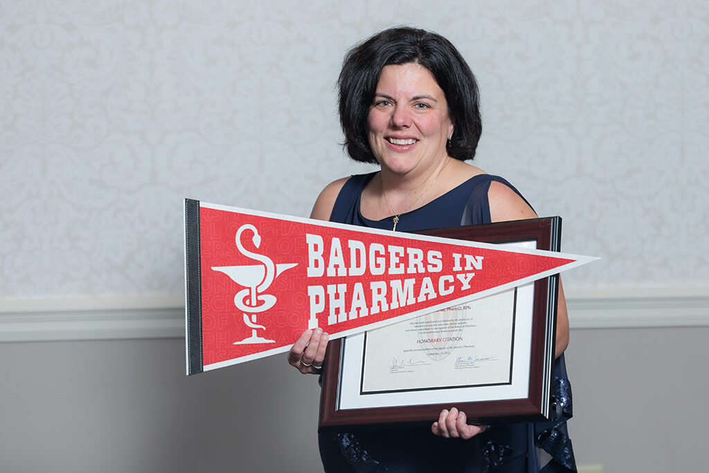 Michelle Farrell with her Citation award and a Badgers in Pharmacy pennant flag.