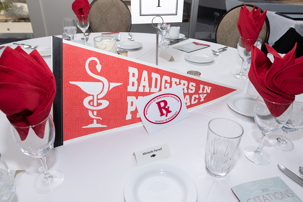A table setting for Michelle Farrell, with a pennant flag, Rx School of Pharmacy Sticker, and empty dishes.
