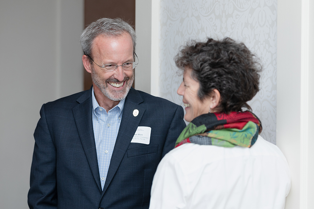 Dave Mott smiling in conversation with Susan Stein.