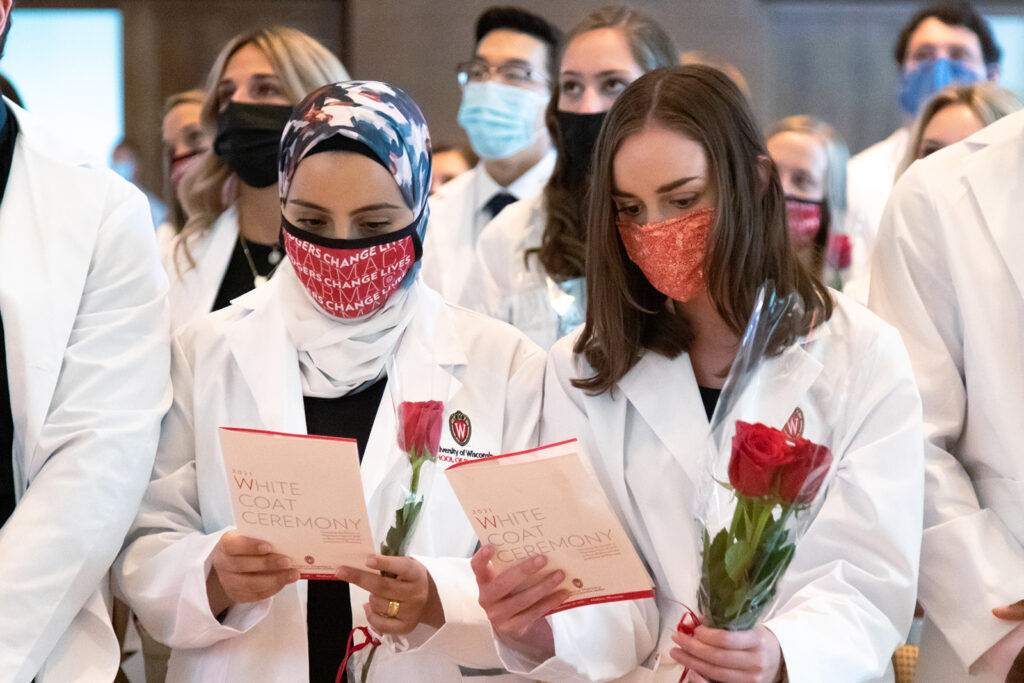 Pharm students holding roses and white coat ceremony pamphlets