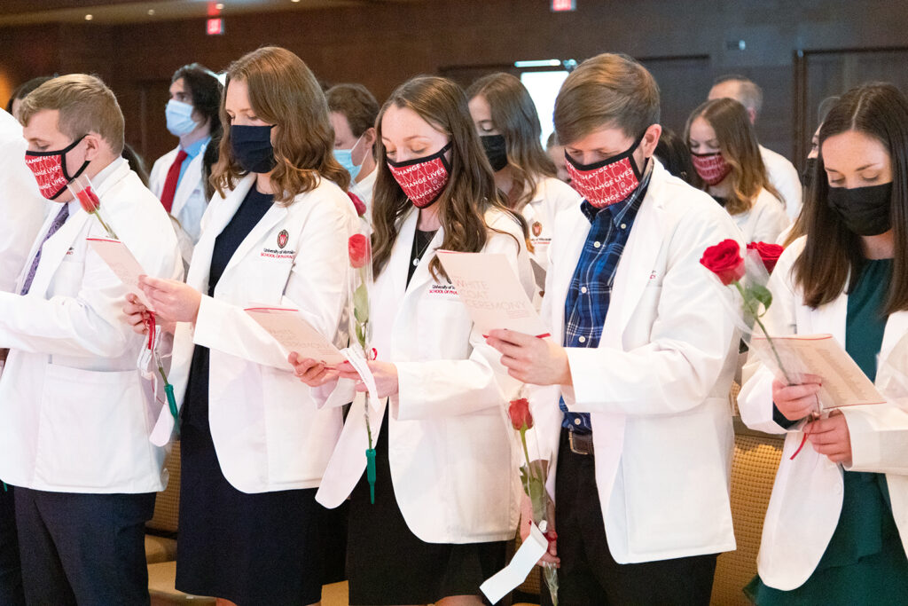 Pharm students holding roses and white coat ceremony pamphlets