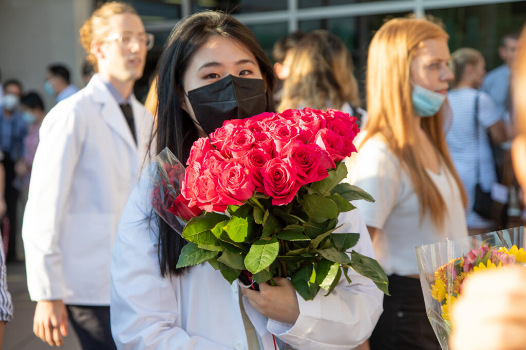 Student holding a bouquet of roses outside after white coat ceremony