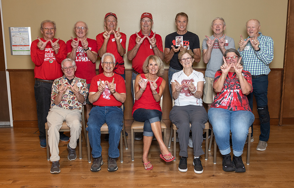 A group photo of Class of 1975 members holding up "W" hands