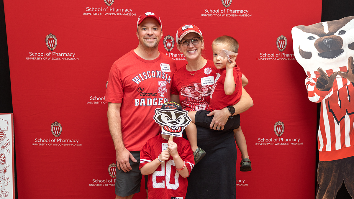 A family with two young children pose next to Bucky Badger while wearing Badger gear