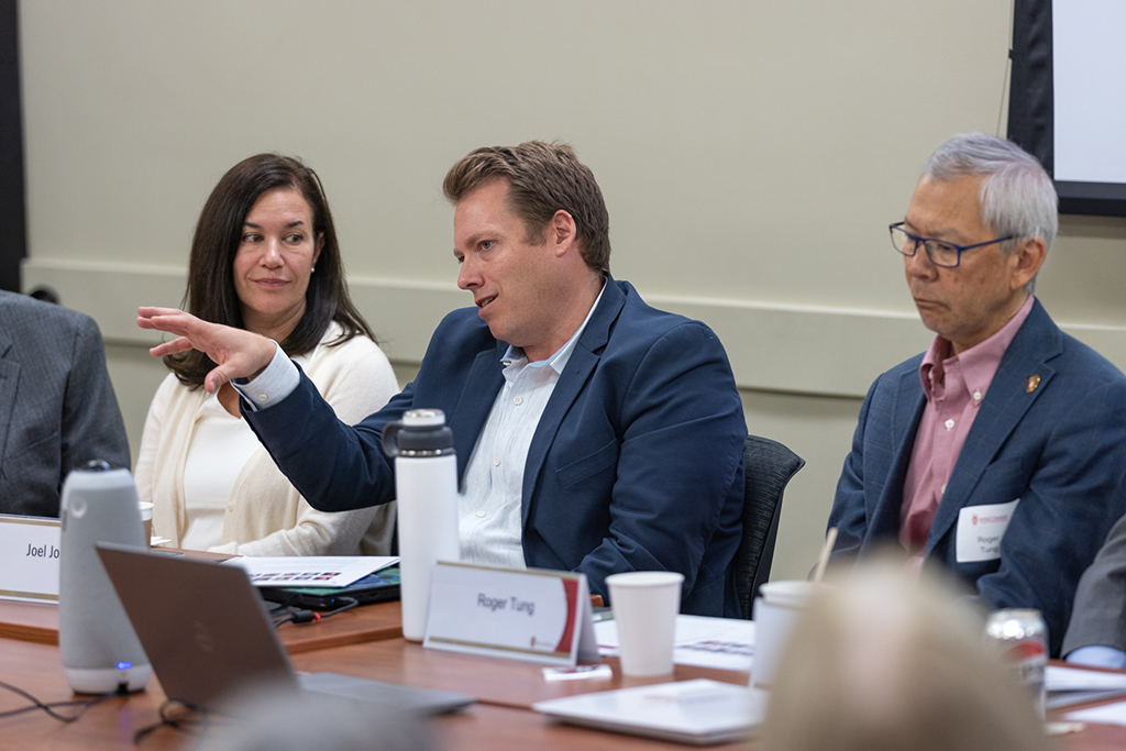 Joel Jones sitting between Roger Tung and Julie Jensen, talking and gesturing with his hands