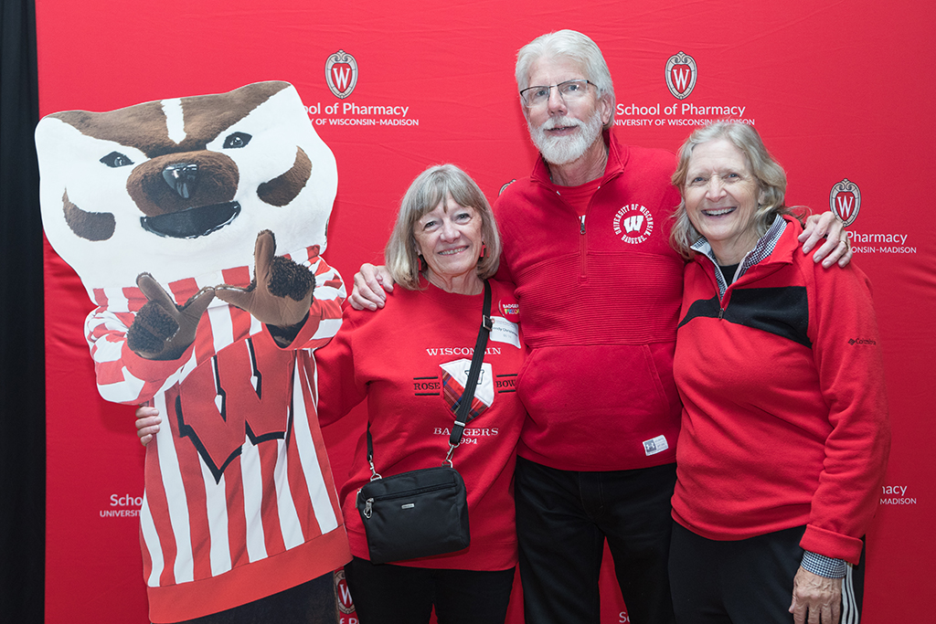 Alumni stand arm-in-arm with Bucky Badger cutout