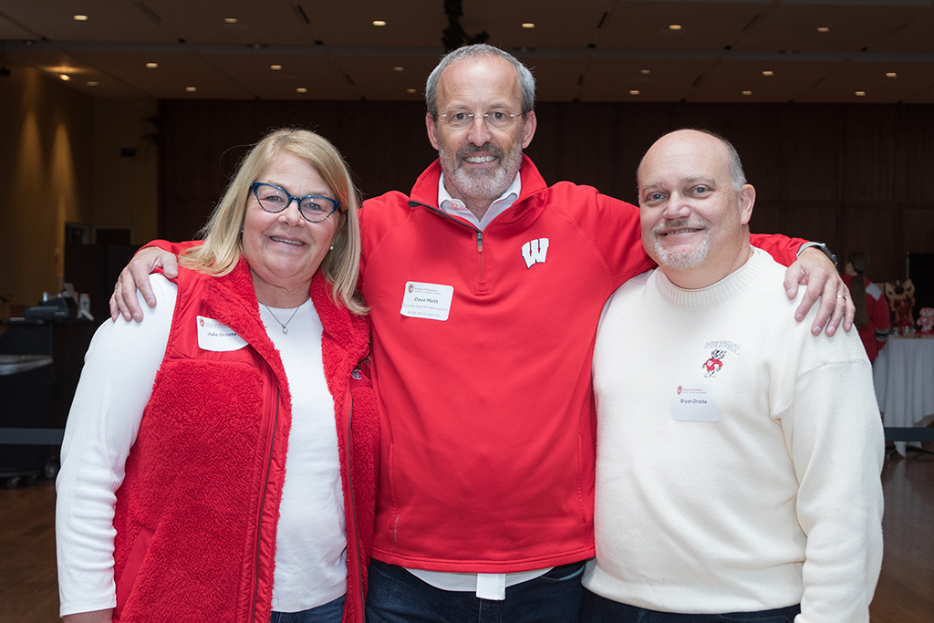 Dave Mott with his arms around School of Pharmacy donors Bryan and Julie Droste