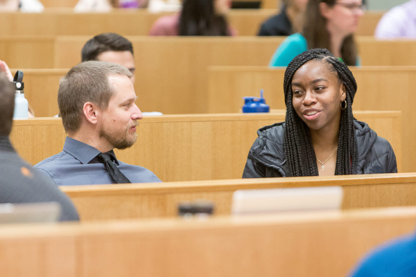 Students speaking together while sitting in lecture hall