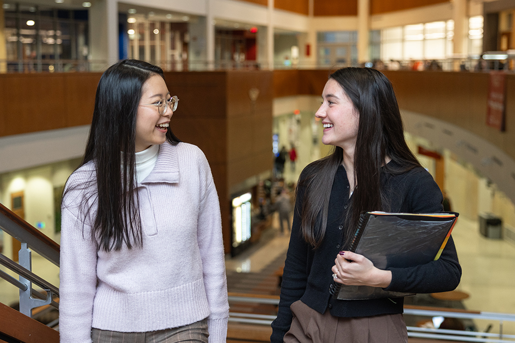 Jessica Liu and Kira Kirsch talk and laugh while they walk up stairs