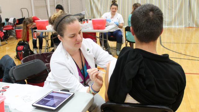 Third-year PharmD student Christina Sanchez administers the meningitis vaccine to a UW-Madison student at the SERF.
