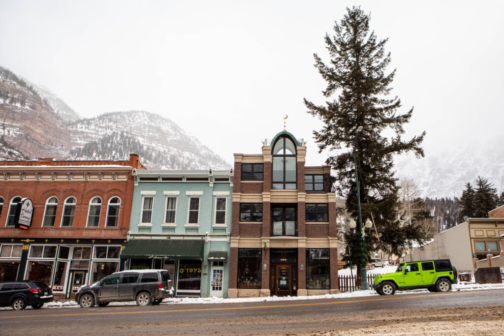 An exterior photo of the Ouray Alchemist with snowy mountains in the background.