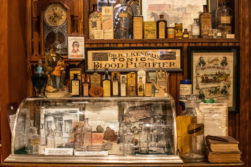 A display featuring many glass bottles and a sign that reads "Dr. B.J. Kendall's Tonic and Blood Purifier."