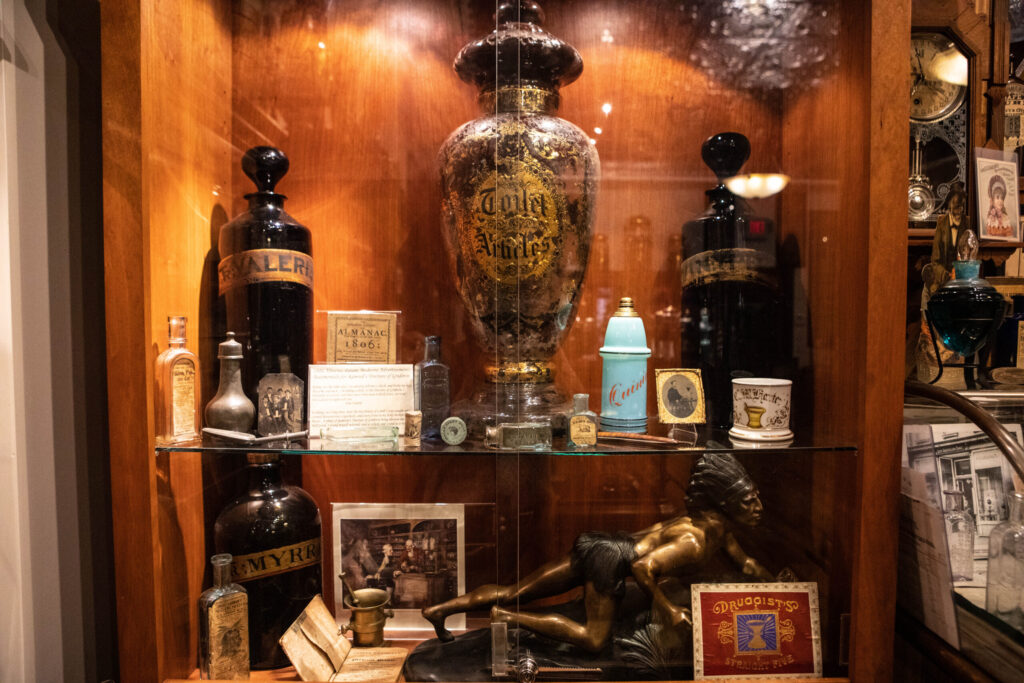 A glass cabinet filled with glass jars and urns.
