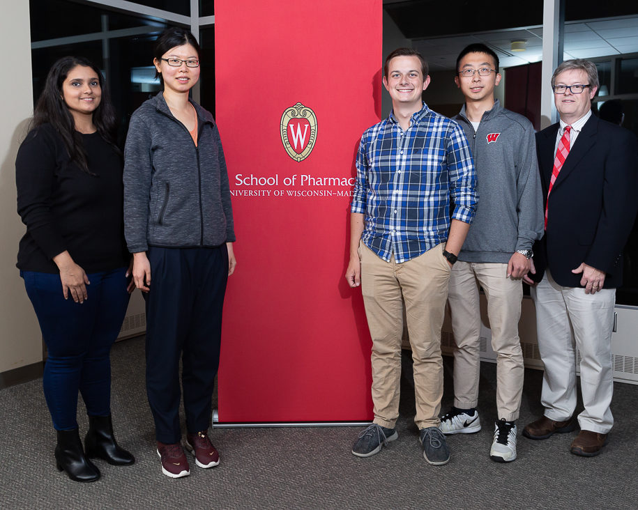 Teaching assistant award-winners Tanvee Thakur, Niying Li, Connor Blankenship, and Xin Yao with Associate Professor Charles Lauhon next to School of Pharmacy banner