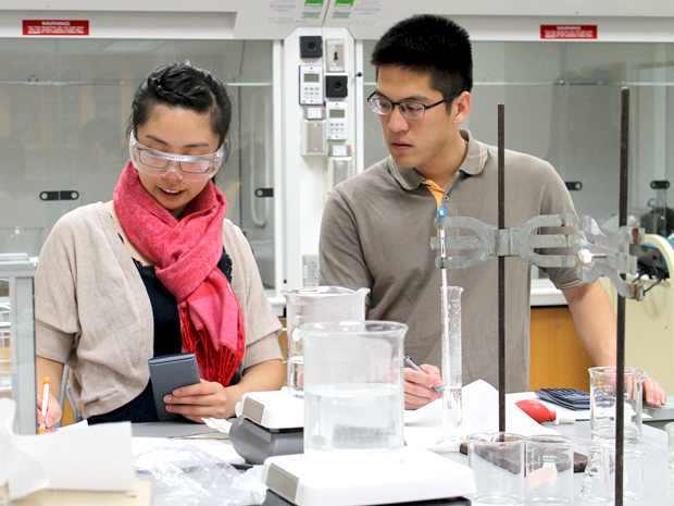 Two lab partners calculate the necessary concentration for a solution in lab